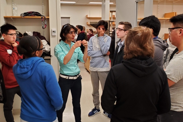 A person lectures to high school students in a lab room. 